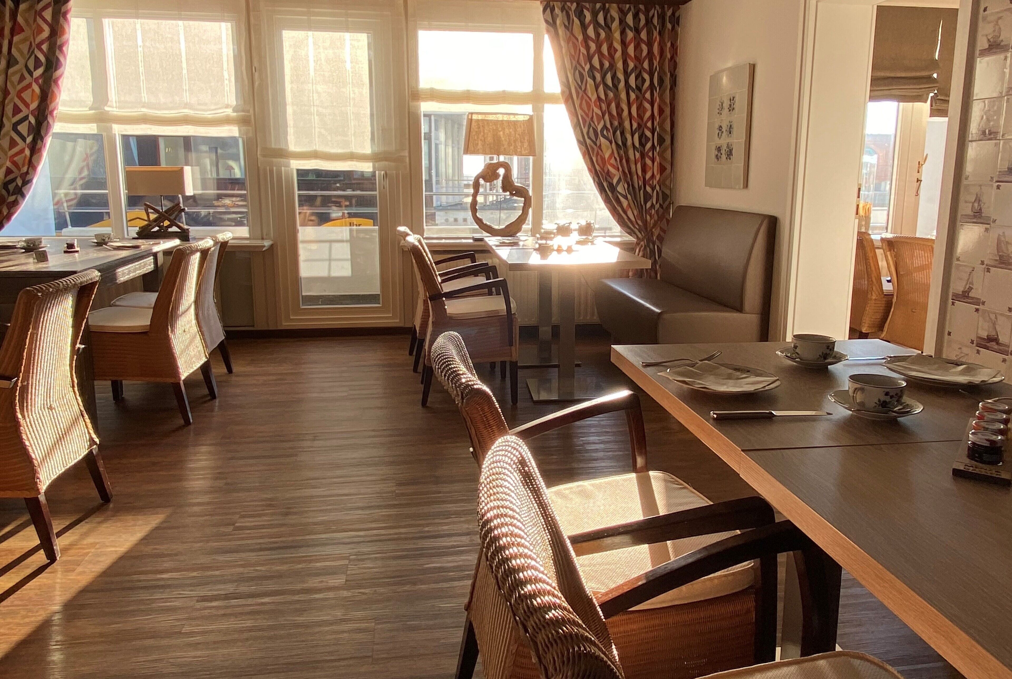 Un comedor con una larga mesa de madera, sillas de mimbre y vistas de la ciudad a través de amplios ventanales.