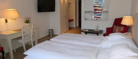 A hotel room with a large bed, a desk, a chair, a TV, and a wall art piece.
