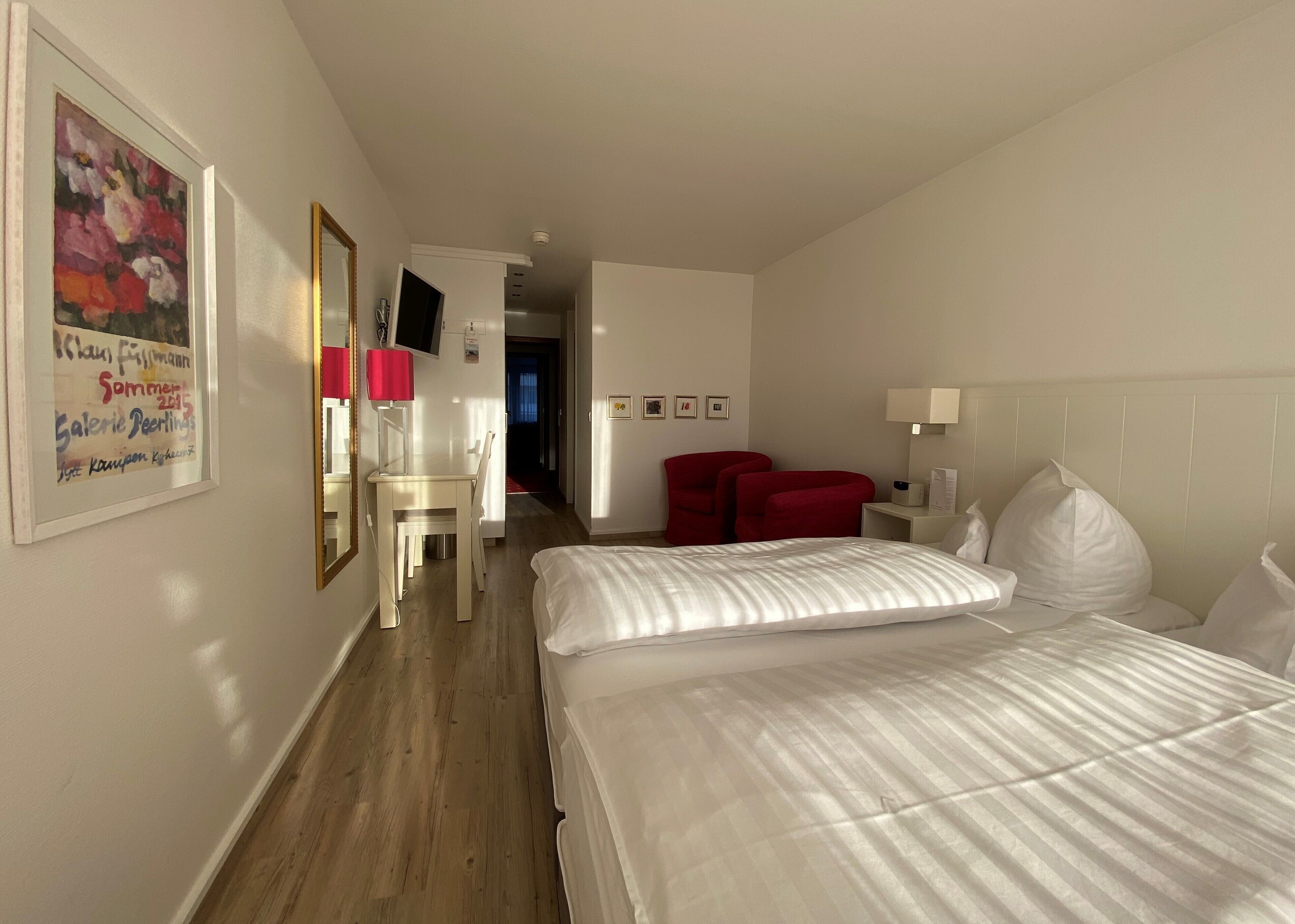 Ein Hotelzimmer mit einem Bett, einem Schreibtisch, einem Stuhl und einem roten Sessel.