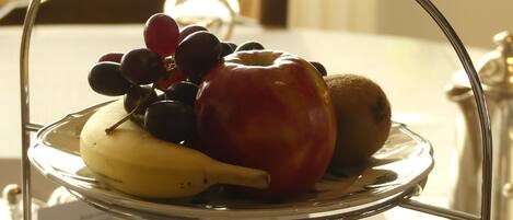 A three-tiered serving tray with various fruits and a small bowl of food, placed on a table with a menu in the background.