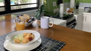 Ein Frühstückstisch mit Obstteller, Orangensaftglas und Croissants.