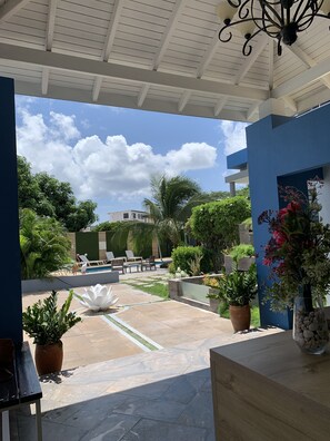 An outdoor patio area with a pool, lounge chairs, and potted plants. - Lilu Apartments Curacao (Willemstad)