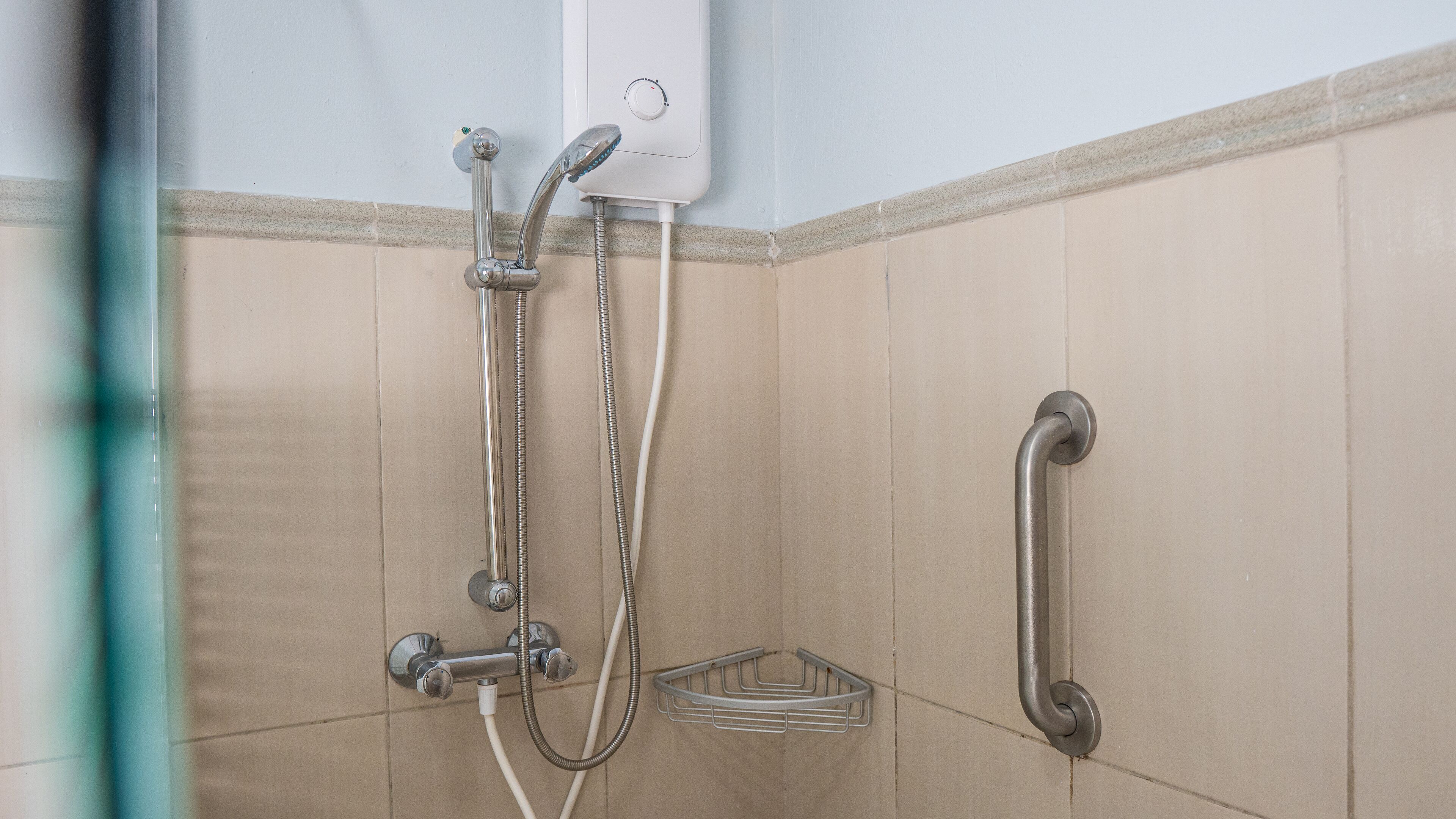 A shower with a handheld showerhead, a handheld faucet, and a wall-mounted faucet.