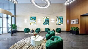 Un vestíbulo moderno con asientos verdes, arte abstracto en la pared e iluminación circular.