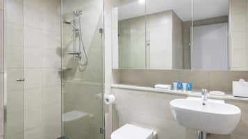 A modern bathroom with a glass-enclosed shower, a white sink, and a toilet.