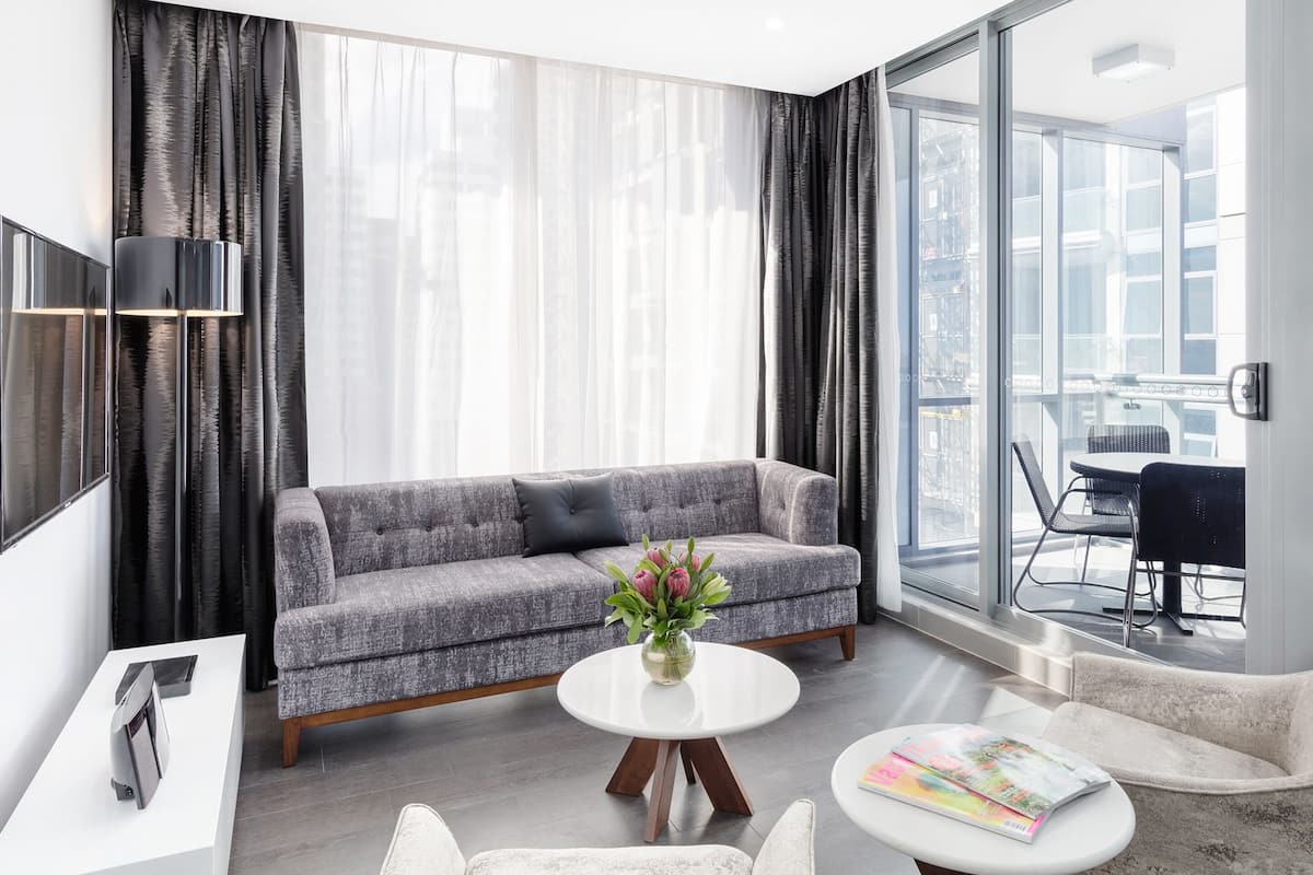 A modern living room with a grey sofa, a white coffee table, and a TV on a white stand.