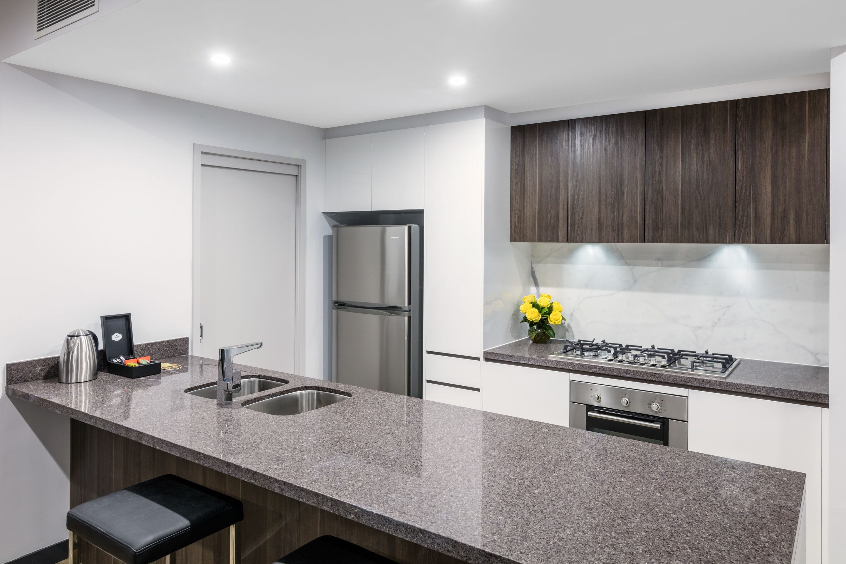 A modern kitchen with granite countertops, stainless steel appliances, and dark wood cabinets.