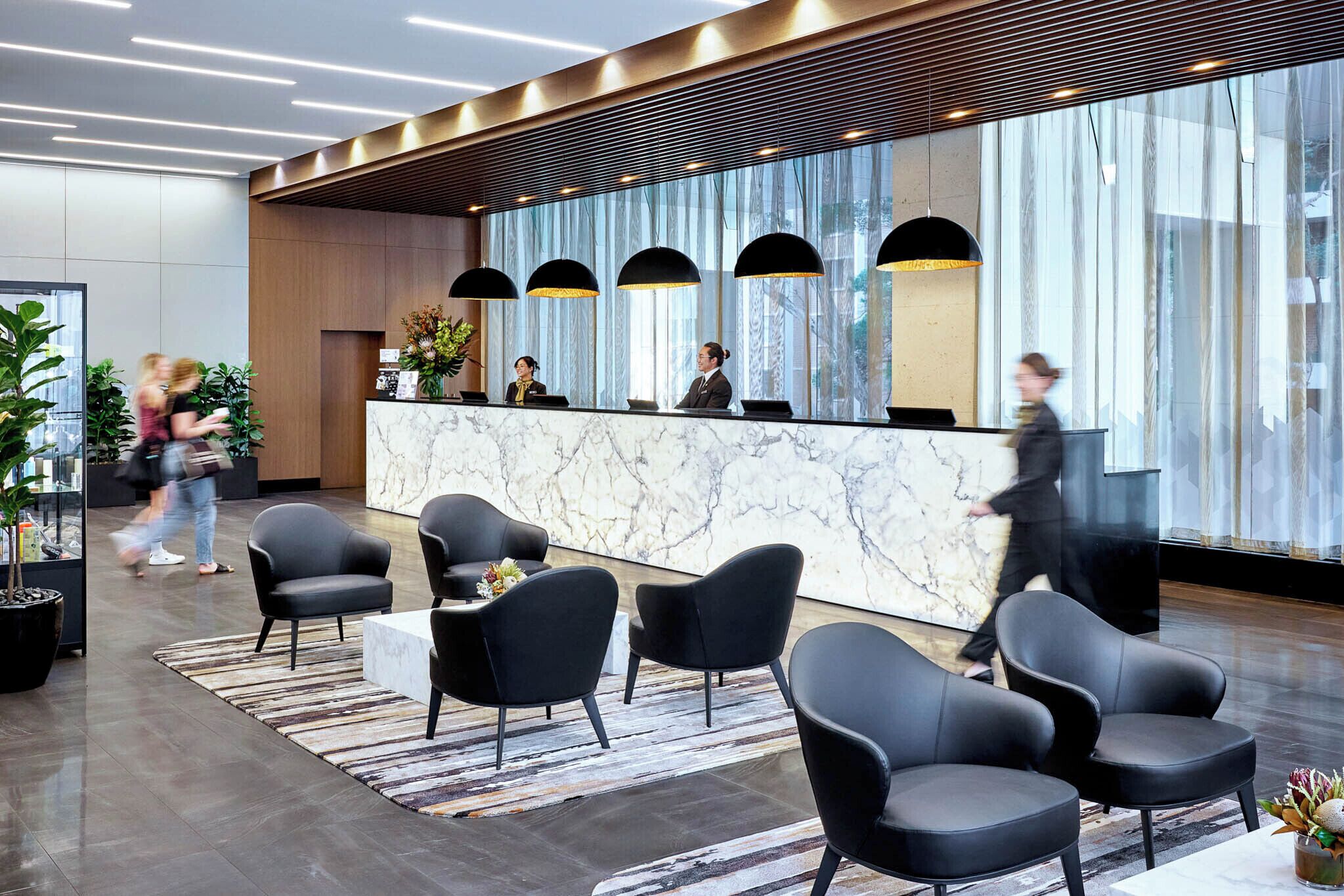 A modern reception area with a marble counter, black chairs, and large windows.