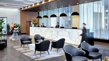 A modern reception area with a marble counter, black chairs, and large windows.