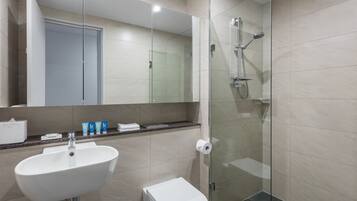 Un baño moderno con cabina de ducha de vidrio, un lavamanos blanco y un inodoro.
