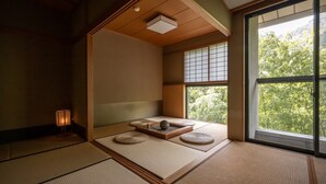 Una habitación japonesa tradicional con suelo de tatami, un panel shoji y vistas a zonas verdes.