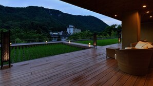 Una terraza de madera con vista a una montaña y un edificio al fondo.