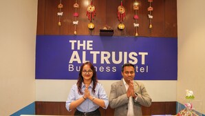 Dos personas frente a un cartel que dice 'The Altruist Business Hotel'.