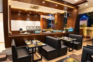 A modern restaurant with a long counter, booths, and a bar area. - The Altruist Andheri Hotel (Mumbai)