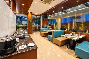 A restaurant with buffet-style service, seating areas, and a view through large windows. - The Altruist Andheri Hotel (Mumbai)
