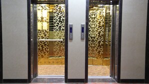 Un ascensor con puertas de cristal ornamentadas y una pared de mármol.
