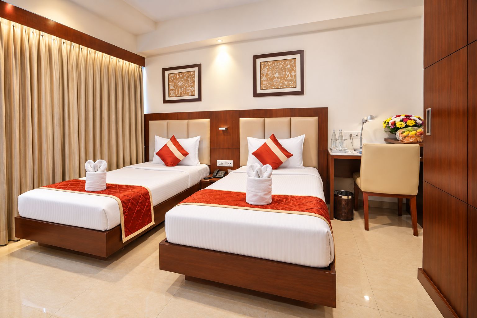 A hotel room with two beds, each with a red and white bedspread, a wooden headboard, and a small table with a vase of flowers.