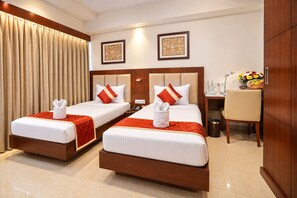 A hotel room with two beds, each with a red and white bedspread, a wooden headboard, and a small table with a vase of flowers. - The Altruist Andheri Hotel (Mumbai)