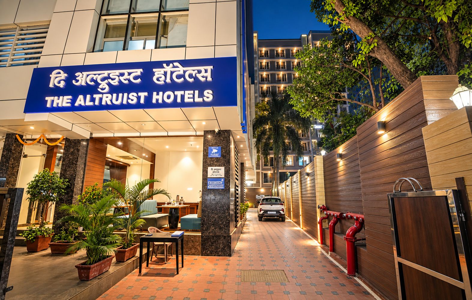 The Altruist Hotels with a modern facade, a welcoming entrance, and a paved pathway leading to the entrance.