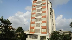 A multi-story building with a modern architectural design, featuring a mix of brick and white panels, large windows, and a flat roof. - The Altruist Andheri Hotel (Mumbai)