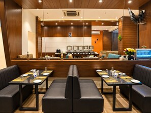 A modern hotel lobby with a reception desk, seating area, and a view of the kitchen. - The Altruist Andheri Hotel (Mumbai)