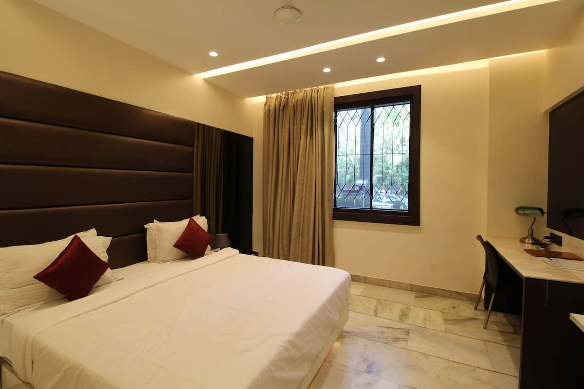 A bedroom with a large bed, a desk, and a window with curtains.