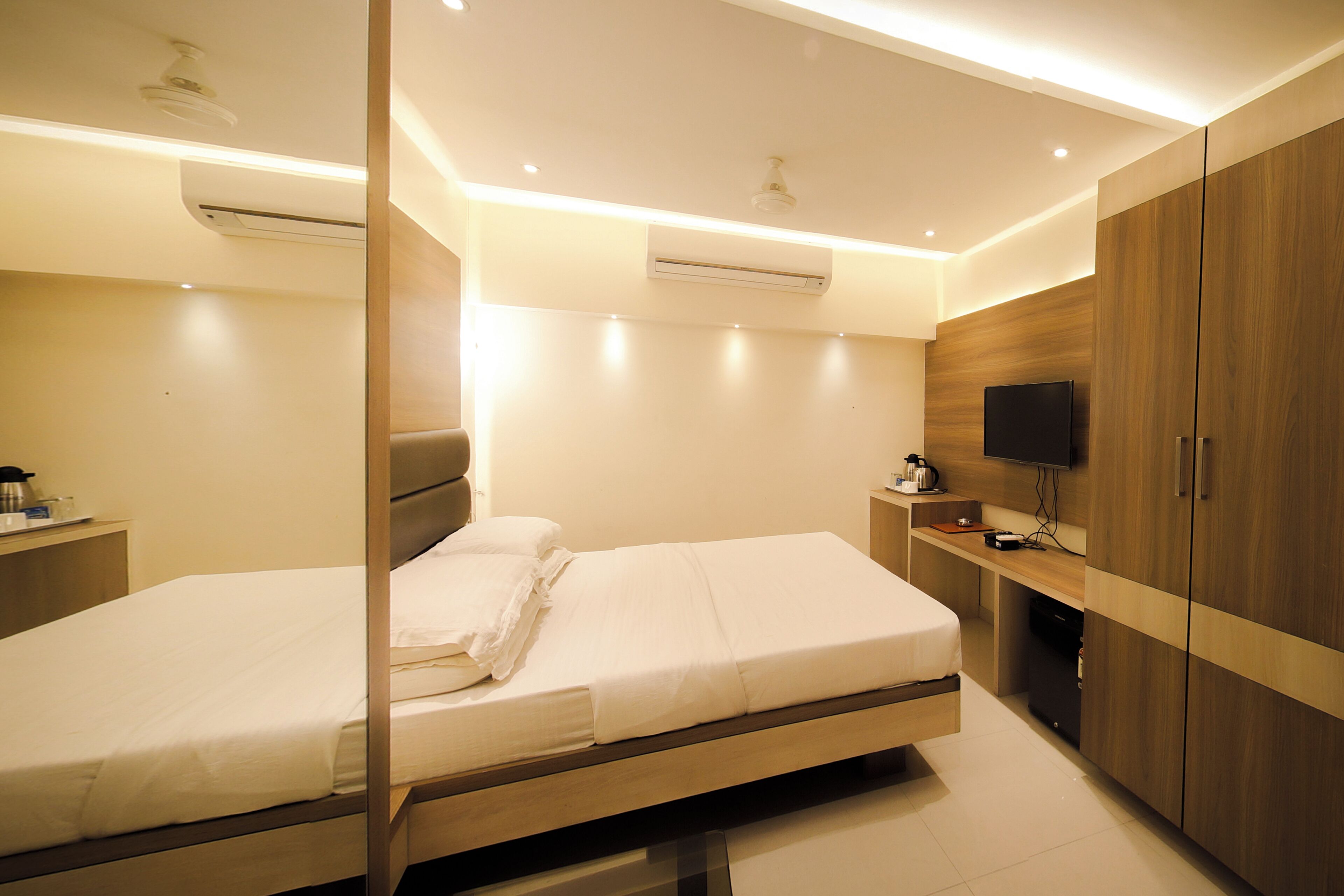 A modern bedroom with a bed, bedside tables, a TV, and built-in wardrobes.