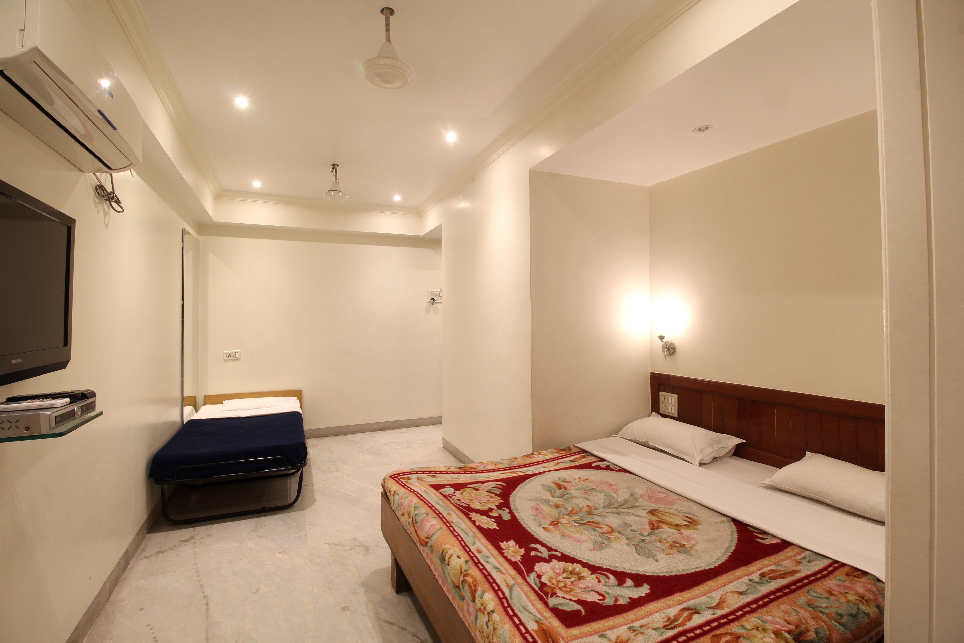 Une chambre d’hôtel avec un grand lit, une petite table de chevet, un téléviseur et un appareil de climatisation.