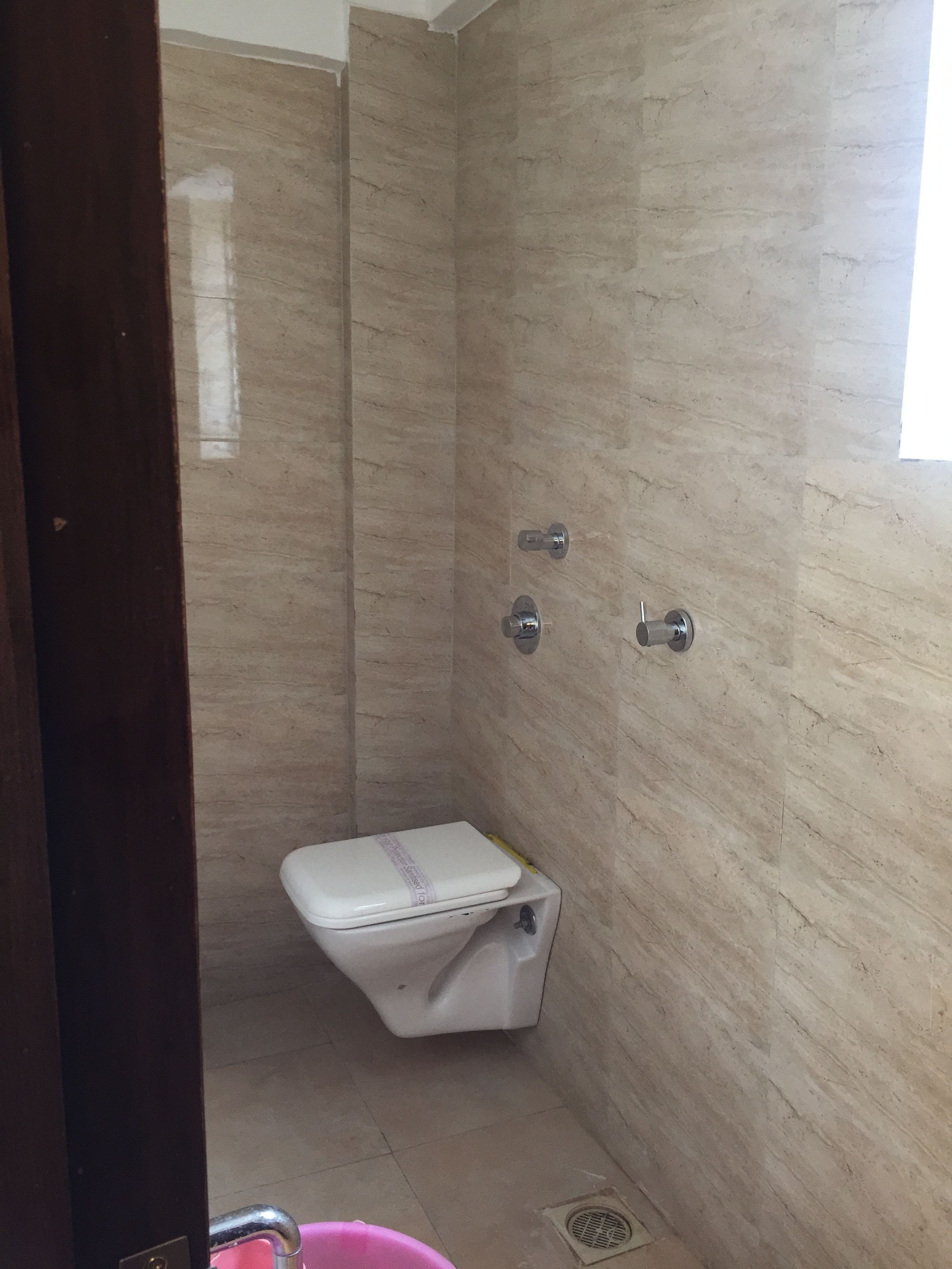 Un baño pequeño con azulejos, un inodoro, una ducha y una ventana.