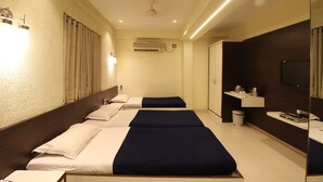 A hotel room with two beds, a bathroom, a TV, and a minibar. - Hotel Shivkrupa (Pune)