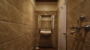 A bathroom with a sink, mirror, and shower. - Hotel Shivkrupa (Pune)