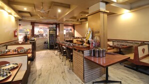 A restaurant with multiple tables and chairs, a counter with a cash register, and a ceiling fan. - Hotel Shivkrupa (Pune)