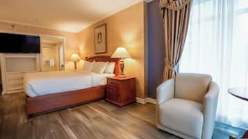 Habitación de hotel con cama, dos mesitas de noche con lámparas, televisión, silla y una pequeña mesa.