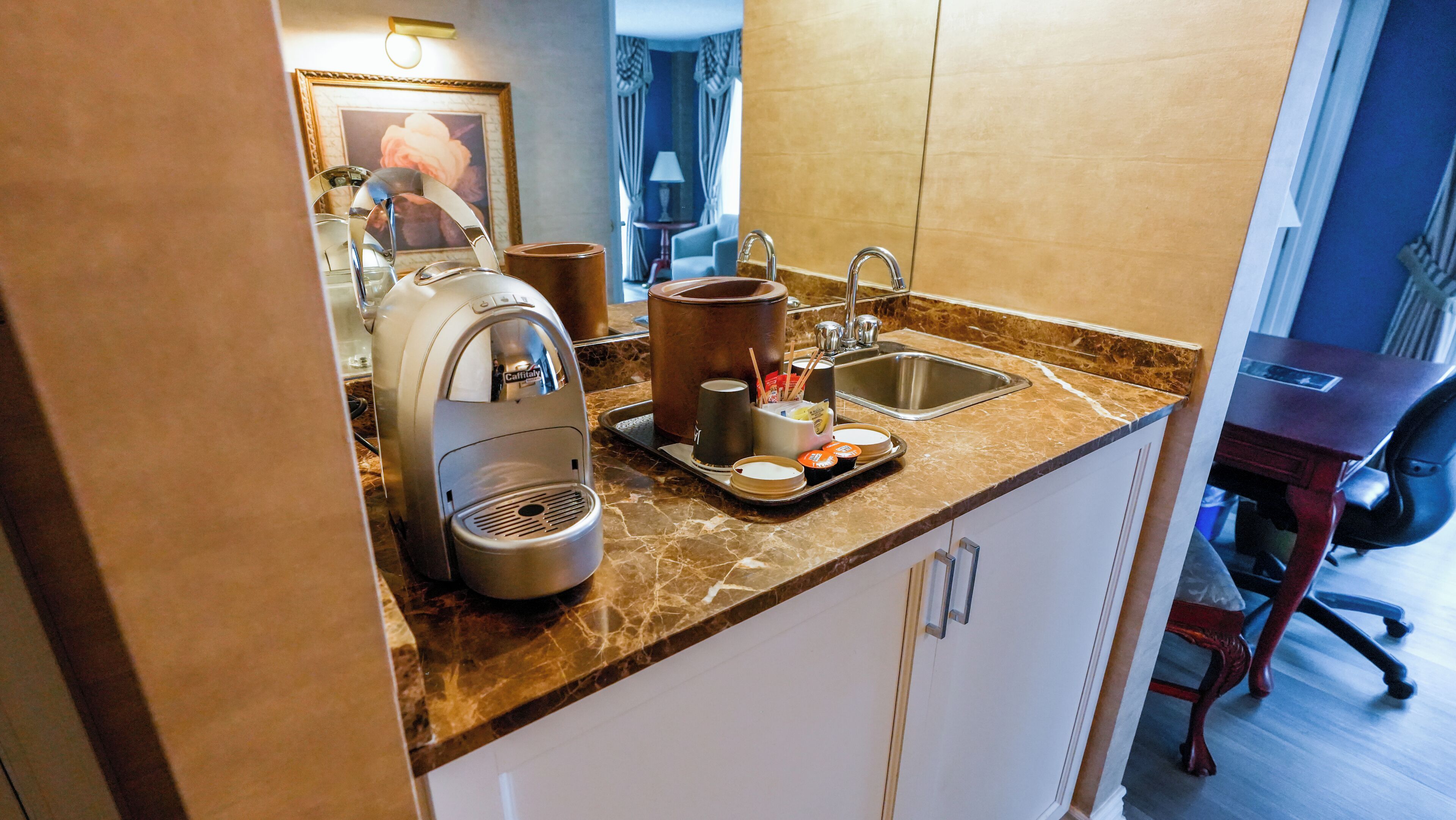 Cocina compacta con cafetera, hervidor y una bandeja con tazas y una taza.
