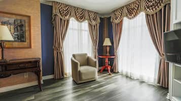 Una habitación con cortinas a rayas, un sofá, una mesa con una lámpara y un cuadro en la pared.