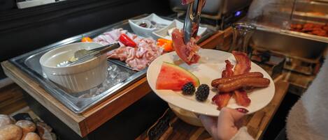 Un bufé con diferentes opciones de comida, incluyendo carnes, quesos y frutas.