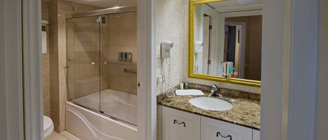 A bathroom with a glass-enclosed shower, a white sink, and a large mirror with a gold frame.