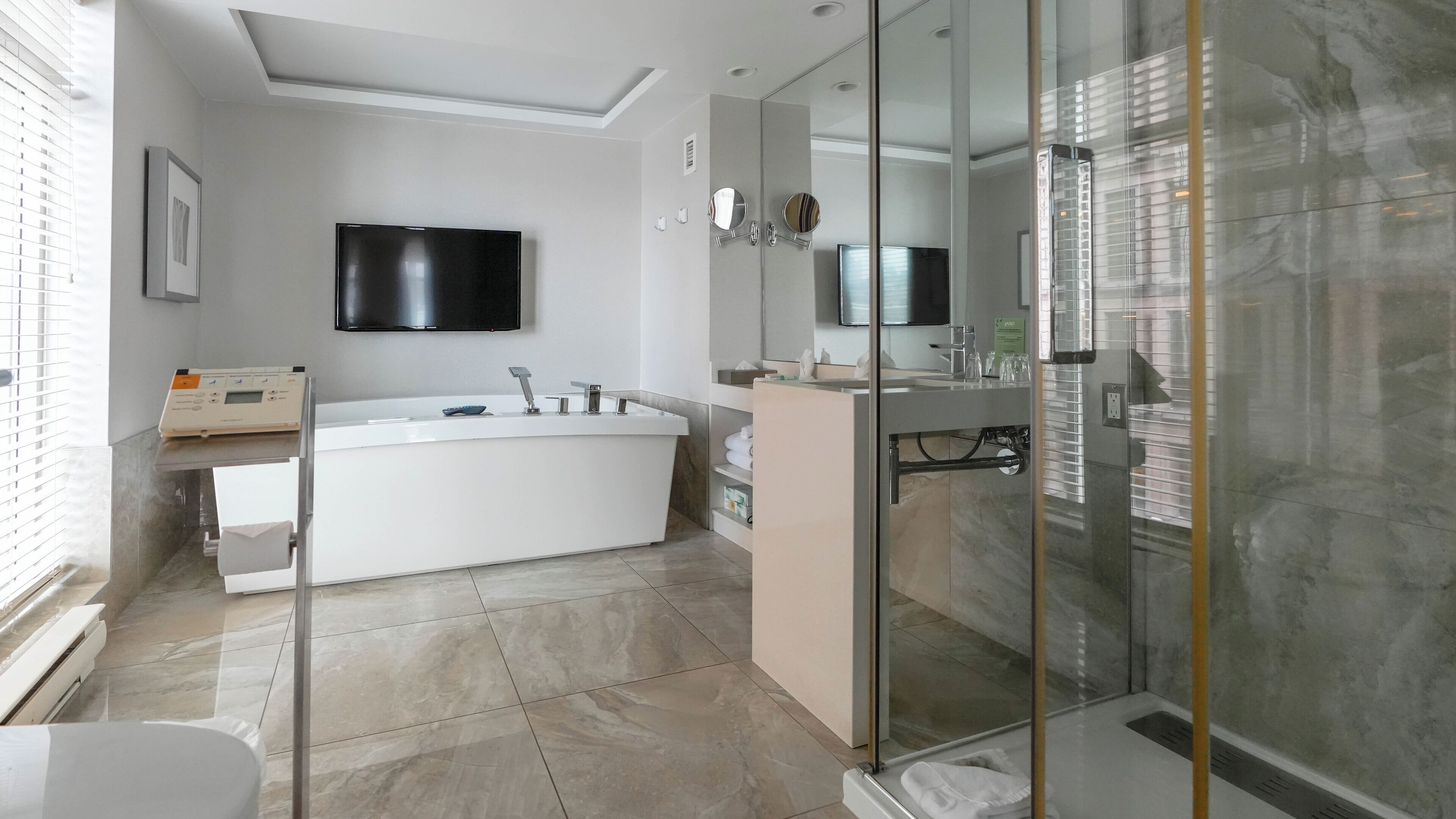 Un baño moderno con una bañera independiente, cabina de ducha con mampara de cristal y un espejo grande.