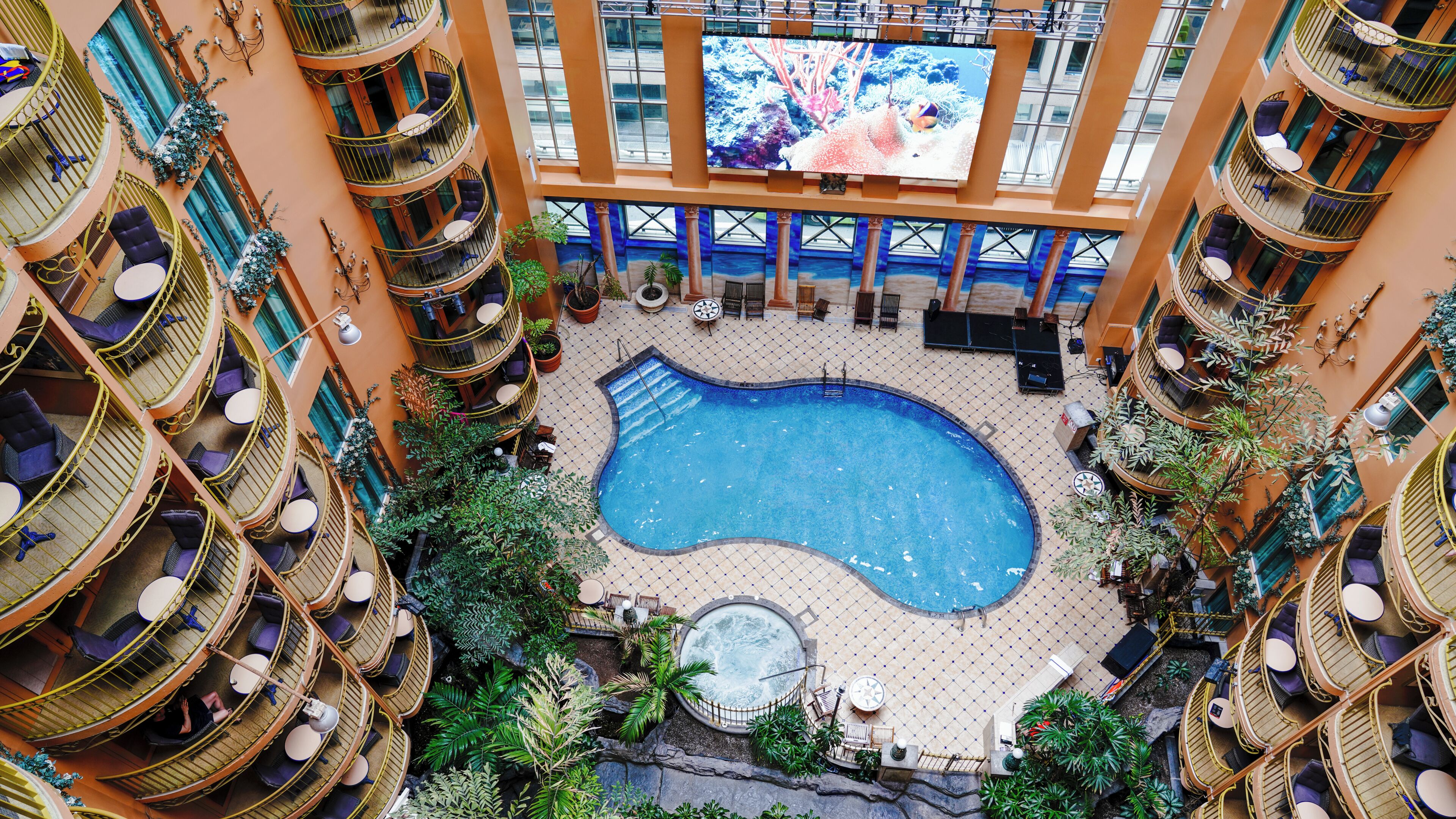 A multi-level hotel with a central swimming pool surrounded by balconies and lounge areas.