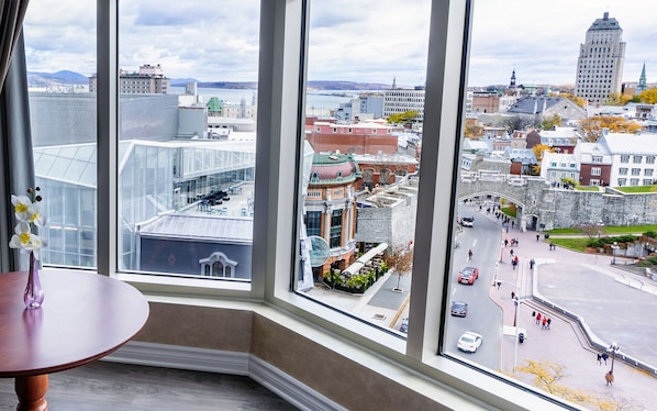 A corner room with a large window overlooking a cityscape, including historic buildings and a waterfront. - Hôtel Palace Royal Centre-Ville par JARO (Québec City)