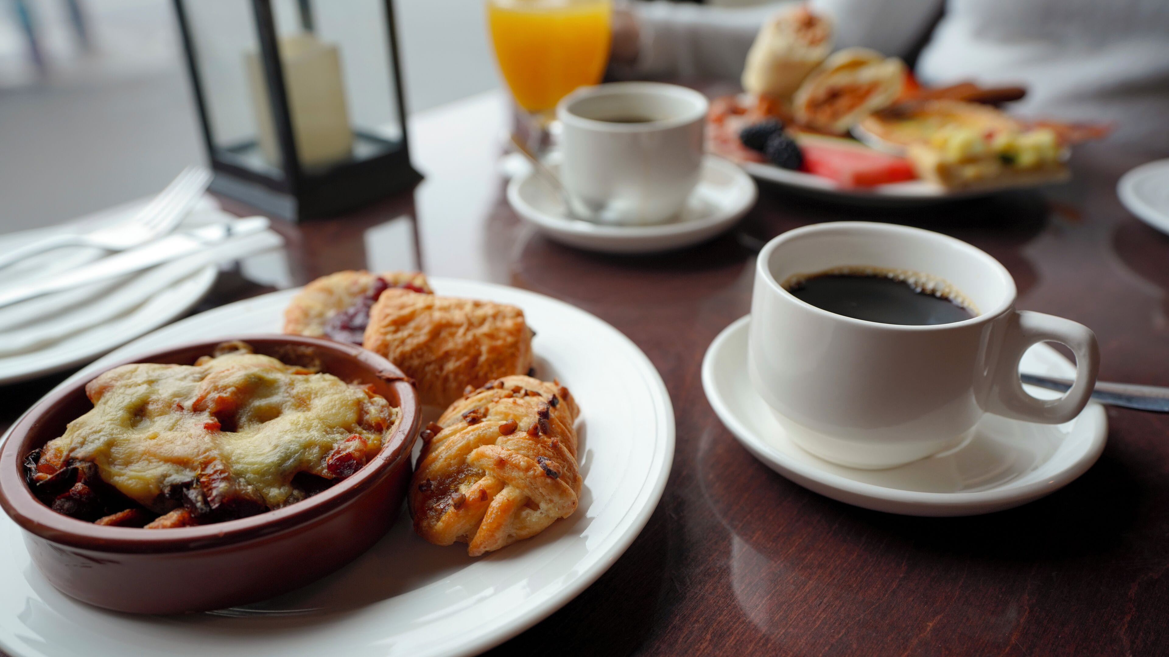 A breakfast table with a bowl of food, a cup of coffee, and a plate with pastries.