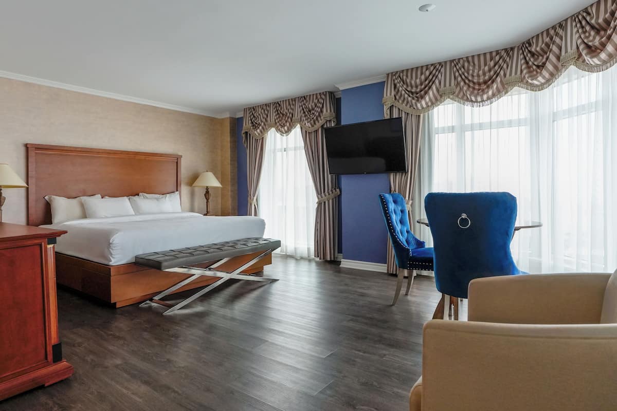 Ett hotellrum med en säng, ett skrivbord, en stol, en tv och gardiner.