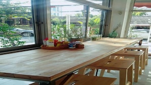 Une table en bois avec des bancs, dans une pièce dotée de grandes fenêtres.