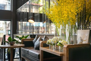 A modern interior with a wooden bench, a cushioned seating area, and a table with vases of flowers.