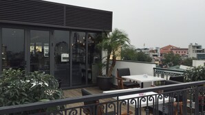 A rooftop terrace with a dining area, potted plants, and a view of the cityscape. - Bespoke Trendy Hotel Hanoi (Hanoi)