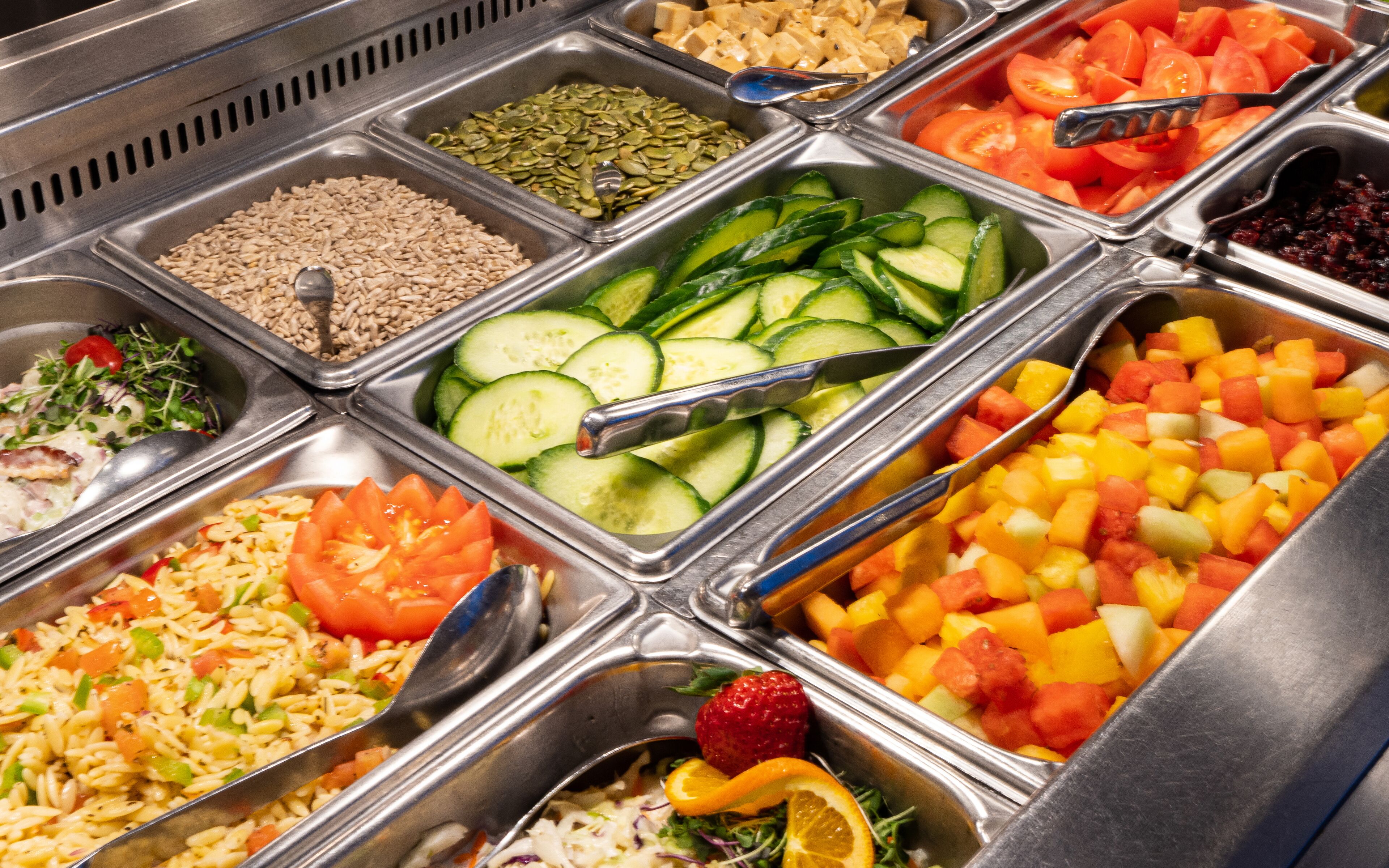 A buffet with various food options including grains, vegetables, and fruits.