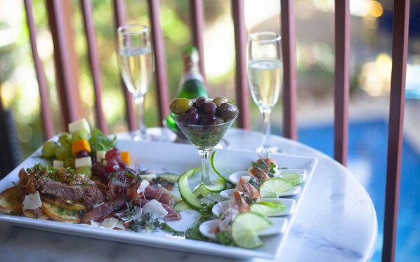 A dining table with a variety of dishes, including a salad, cheese, and meat, along with two glasses of white wine.