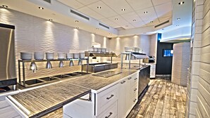 A modern kitchen with a wooden countertop, stainless steel appliances, and a tiled backsplash. - L'Hôtel Québec par JARO (Québec City)