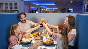 A family dining at a restaurant with a booth, a table with food and drinks, and a menu.