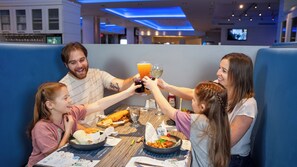 A family dining at a restaurant with a booth, a table with food and drinks, and a menu.